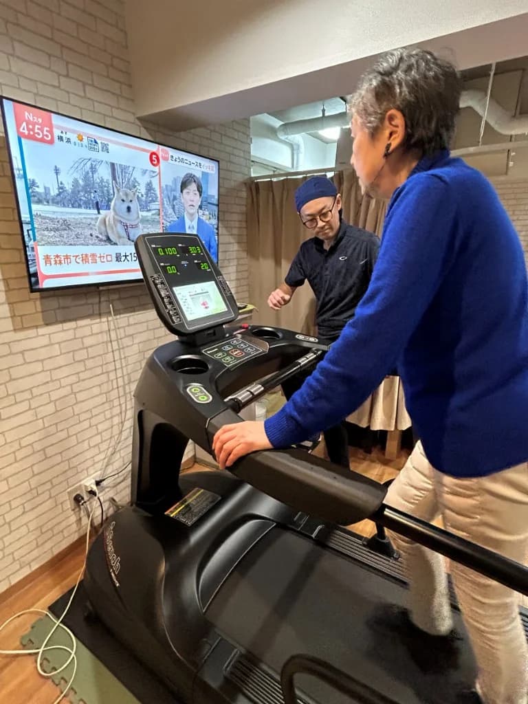 スタッフが見守る中、利用者がトレッドミルで歩き方の練習をしている様子