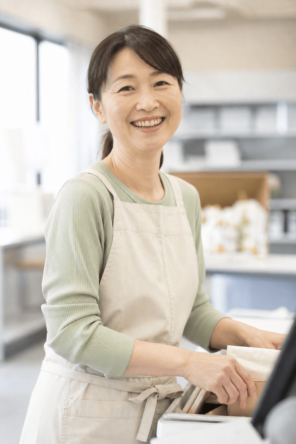 職場で楽しそうに立ち仕事をする50代の女性
